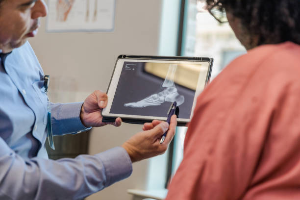 The podiatrist helps to review and explain the findings of the x-ray to his patient.